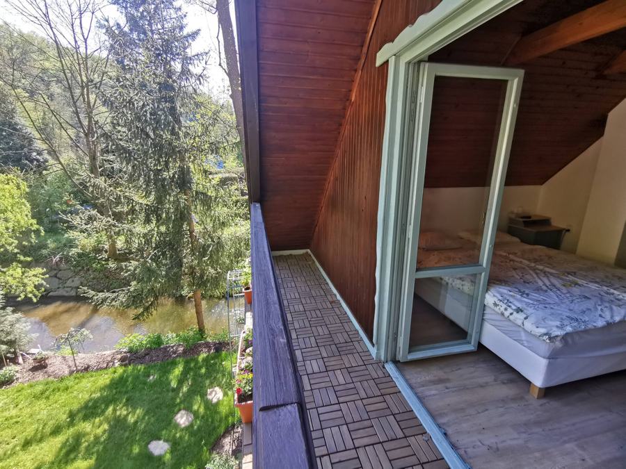 Balkon u ložnice s výhledem na potok a smrky