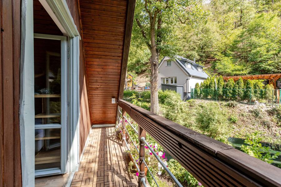 Balkon s truhlíky květin a výhledem do údolí