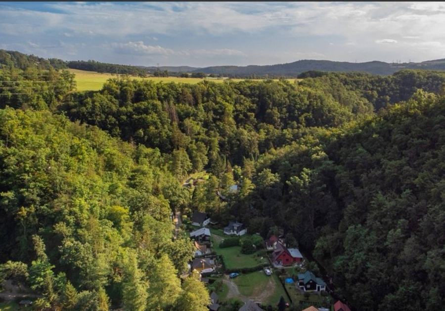 Lesnaté údolí s chatovou osadou z ptačí perspektivy
